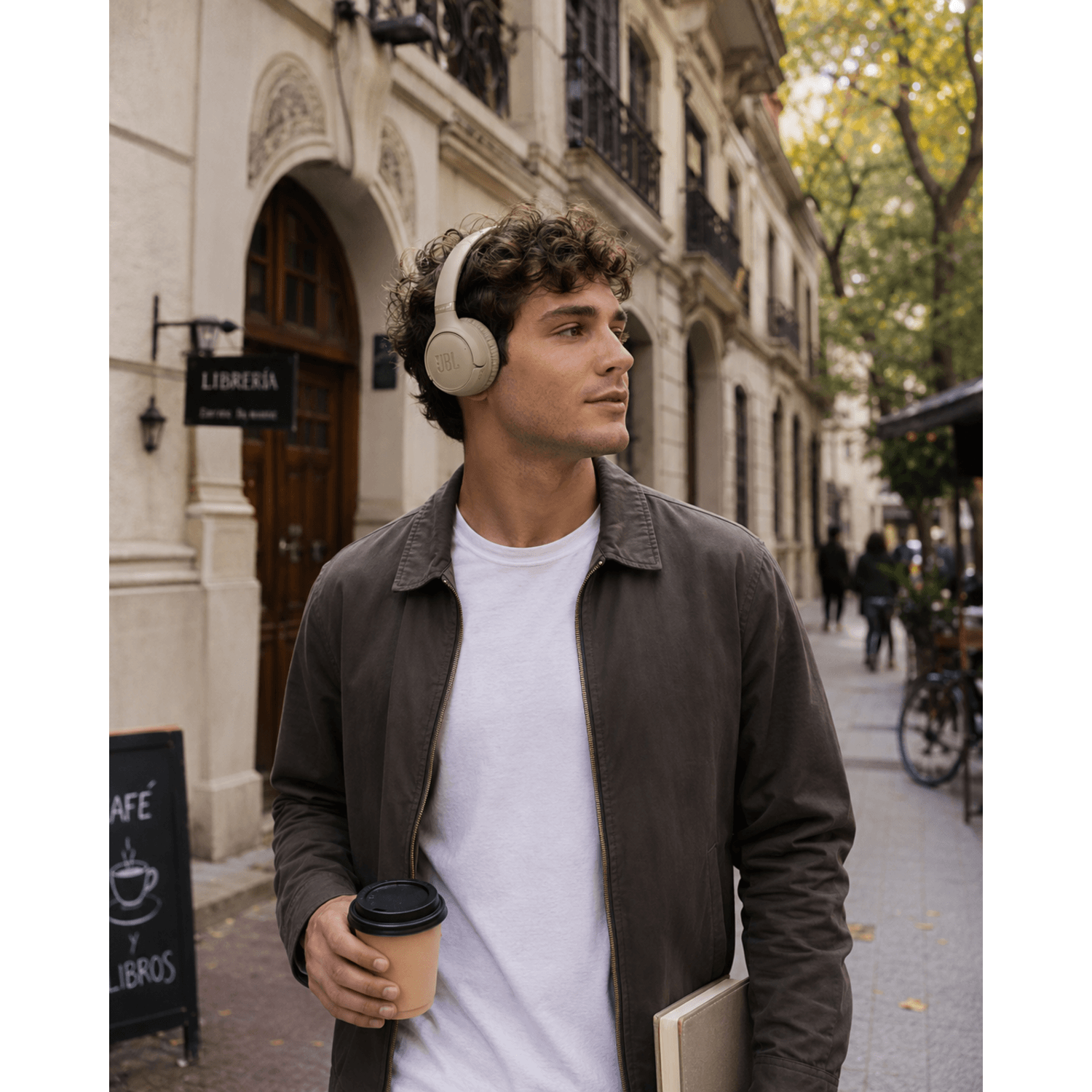 Hombre usando audífonos bluetooth JBL Tune 530BT en la calle, sosteniendo un café en un ambiente urbano.