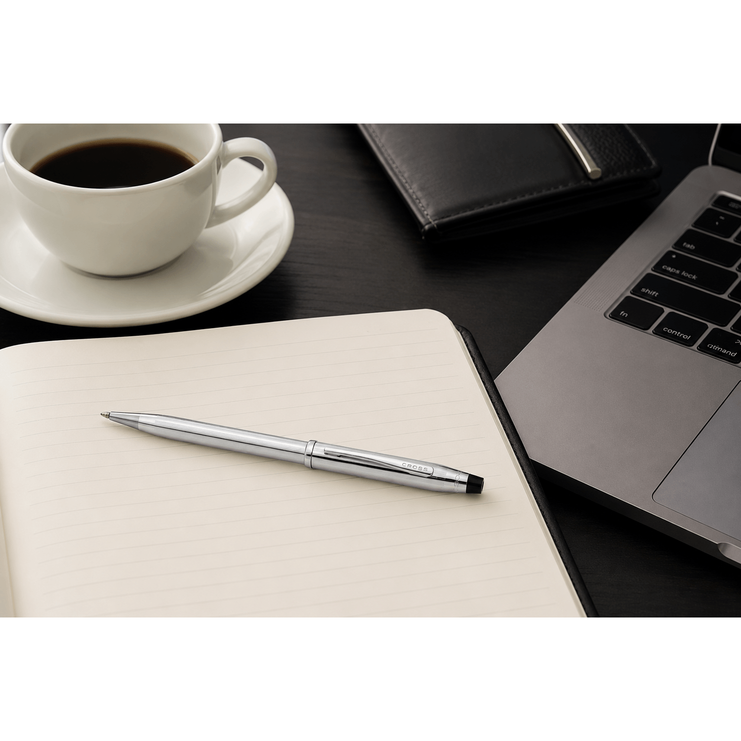 Bolígrafo Cross Century II Cromado Brillante 3502WG Premium sobre un cuaderno junto a una taza de café y una laptop.