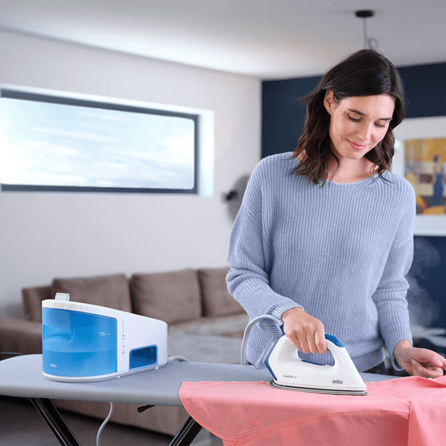 Mujer usando el centro planchado Braun CareStyle 3 Pro, planchando una camisa en casa.