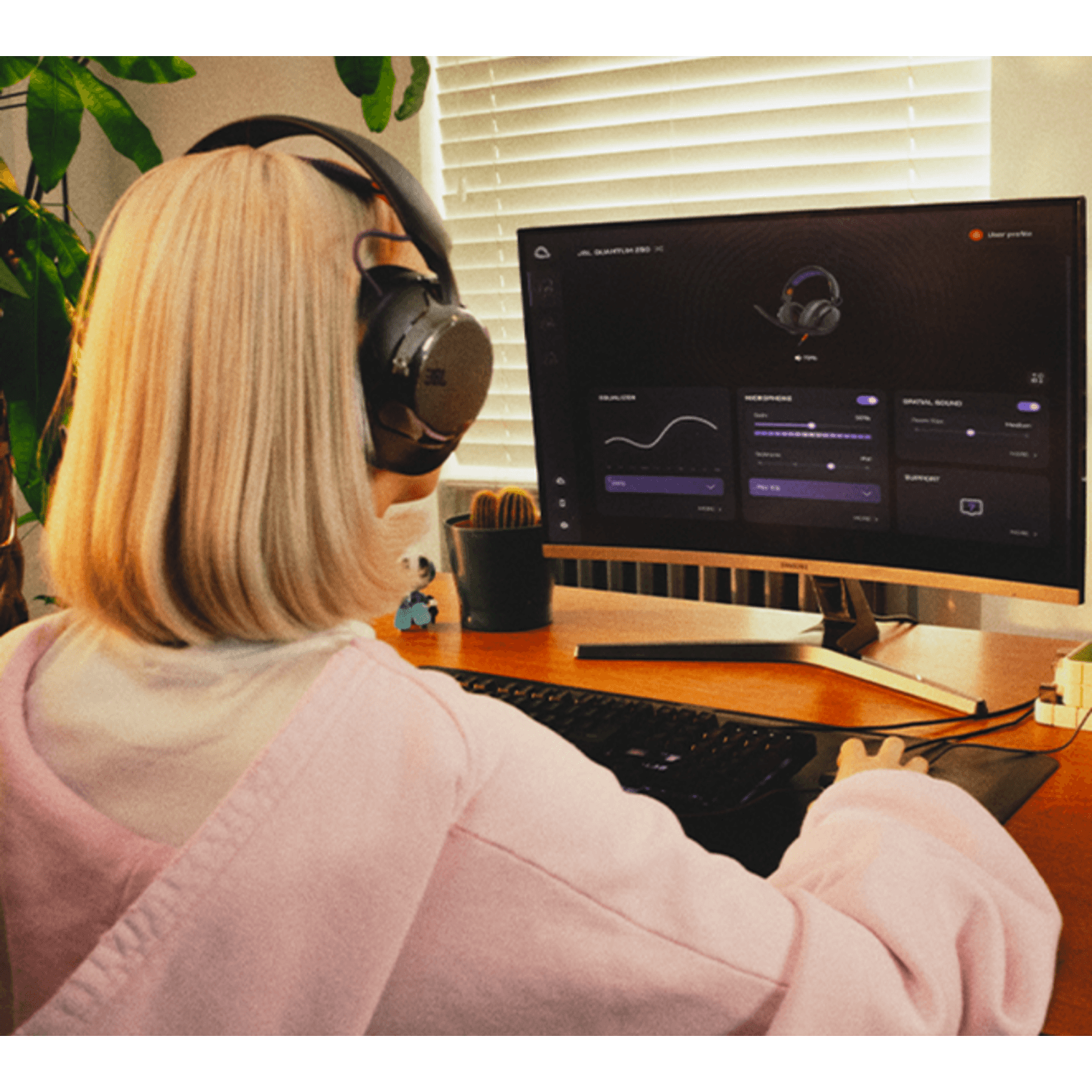 Mujer usando audífonos gamer JBL Quantum 250 mientras ajusta la configuración en su computadora.