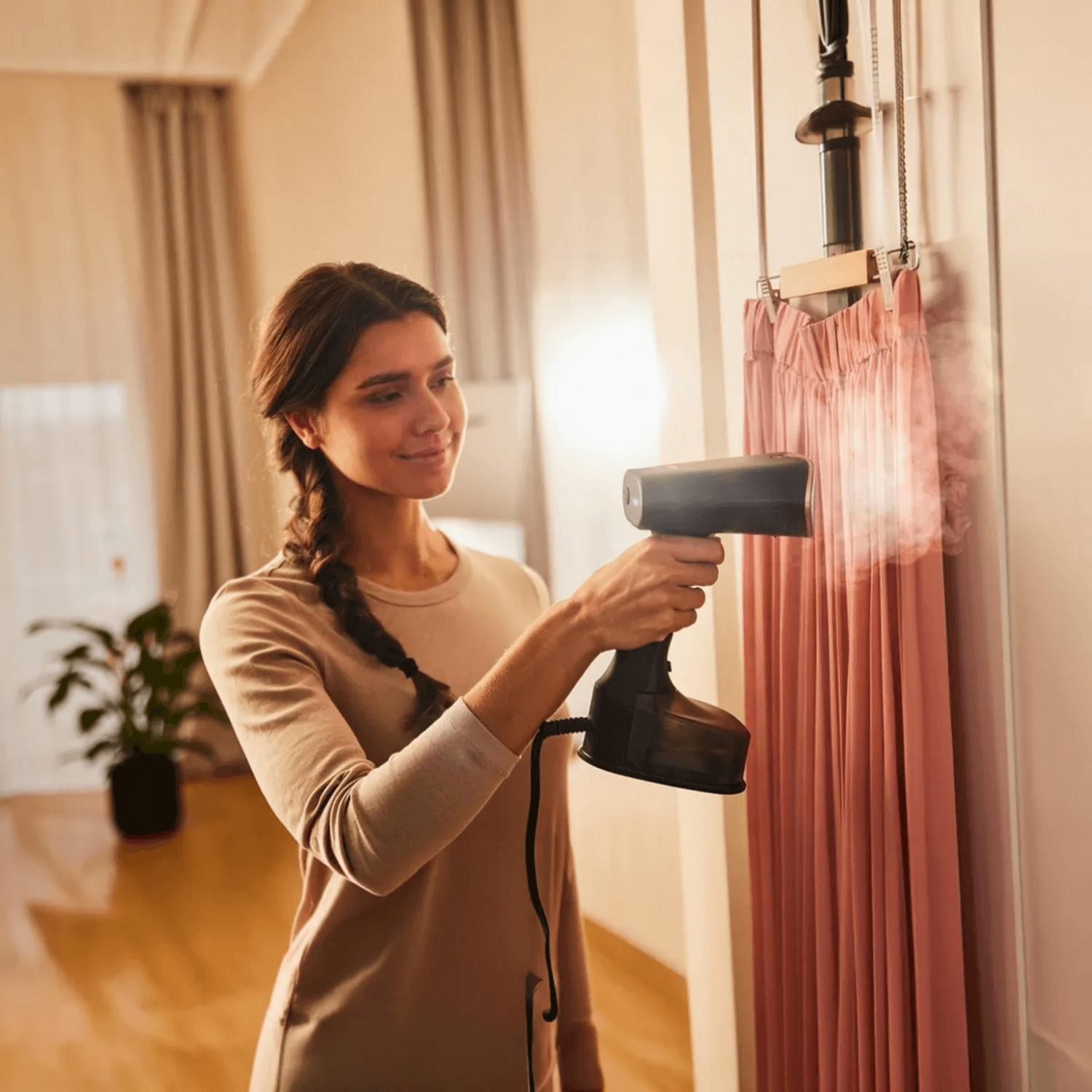 Mujer usando plancha vertical Braun QuickStyle 7 para vaporizar cortinas de forma rápida y eficiente.