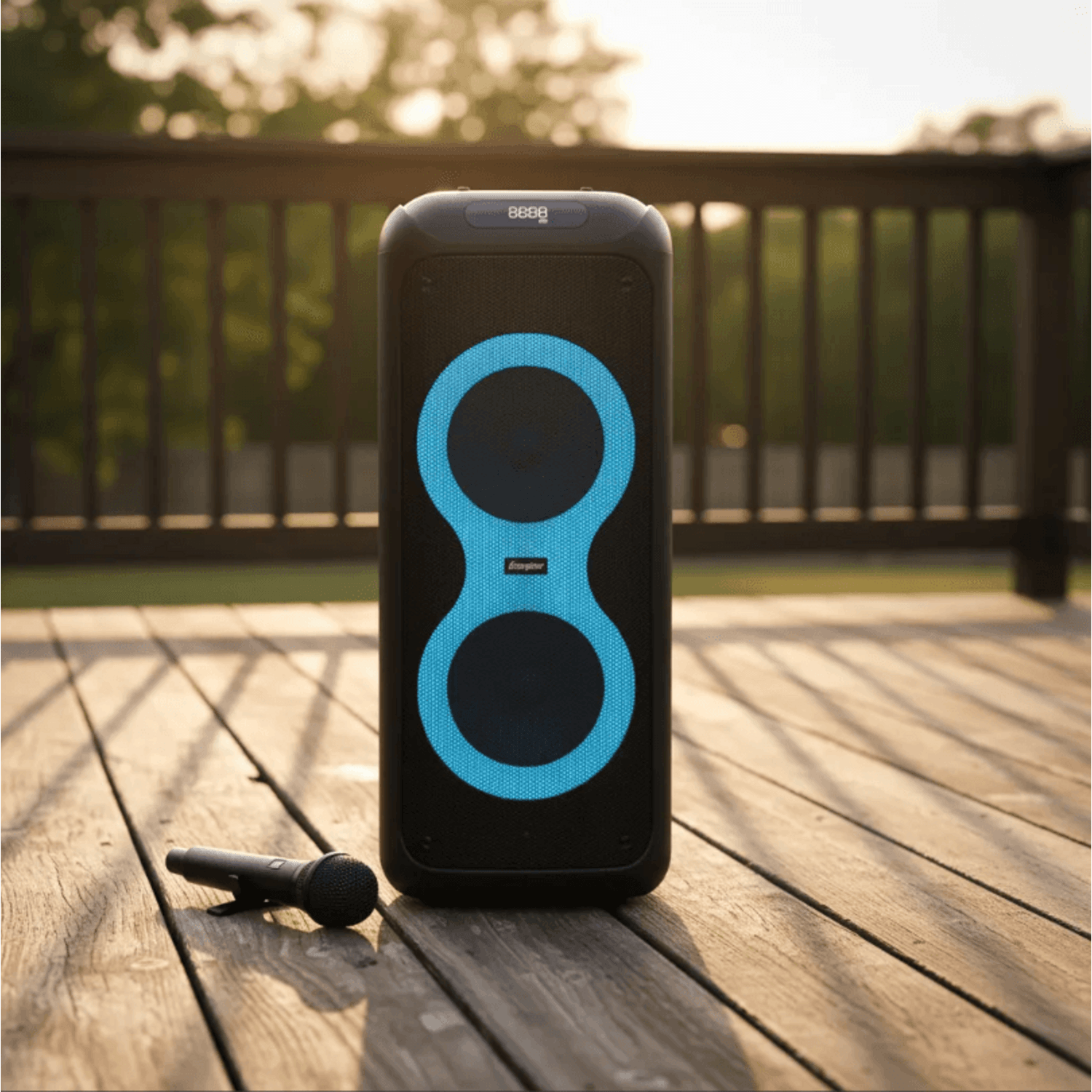 Torre de Sonido Karaoke Energizer Titan Box BTS536 con micrófono en un patio al atardecer.