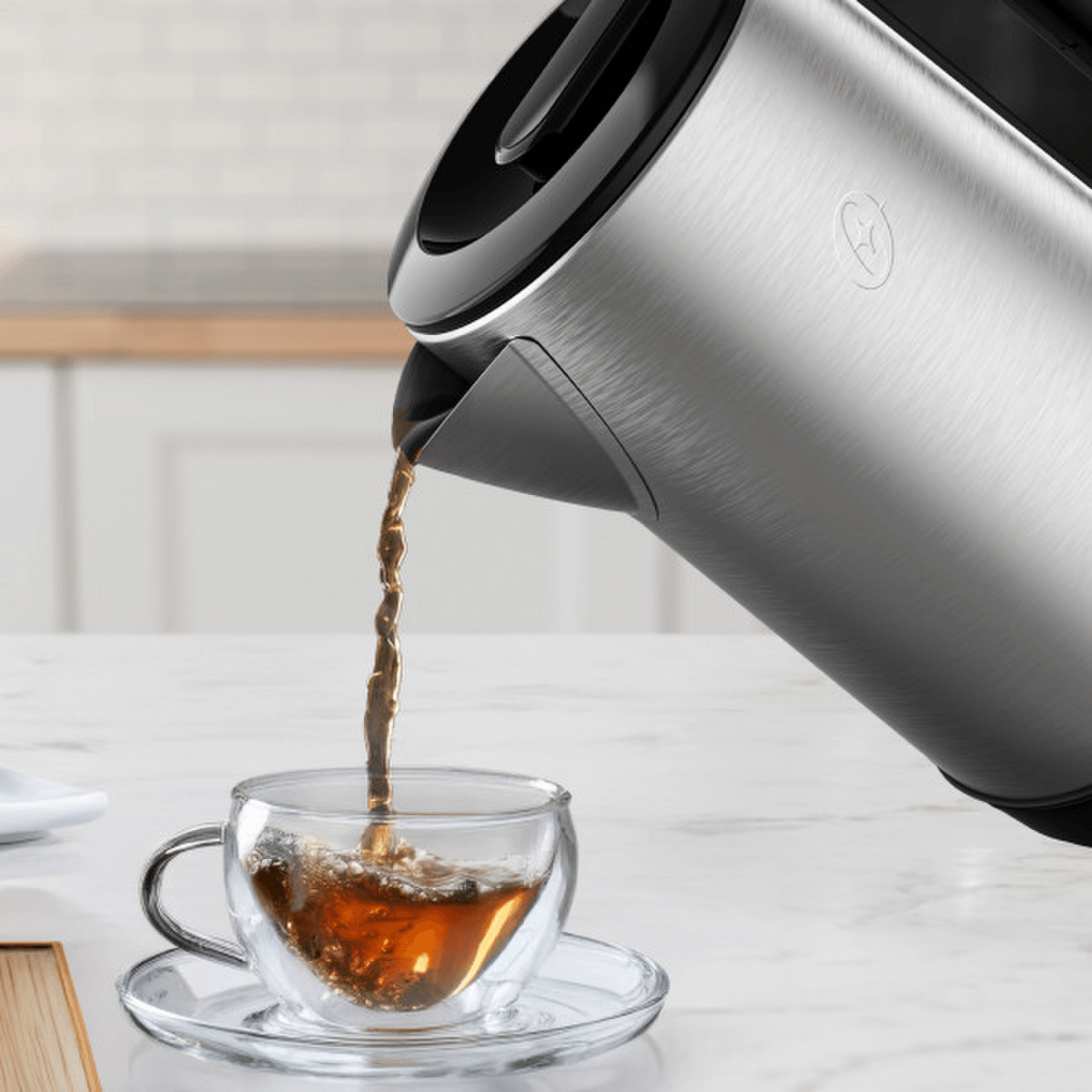 Hervidor Oster 2L 1200W Acero Inox Apagado Auto 2220516 vertiendo agua caliente en taza de té.